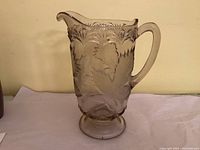 Full side view of pressed glass pitcher showing maple leaf pattern and handle