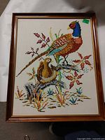 Full view of framed needlepoint showing both birds and frame