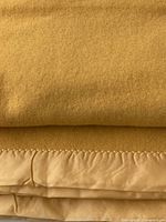 folded mustard wool blanket showing satin bound edge