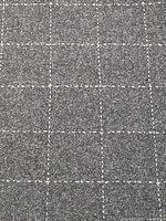 Close-up of wool fabric showing dark charcoal weave and cream check