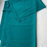 Full view of folded turquoise wool yardage showing length and selvage edges