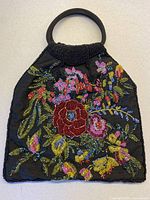 Full view of hand-beaded handbag showing floral beadwork, wood handles