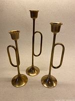 Front view of three brass horn candlesticks