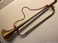 Full view of brass bugle horn with red cord