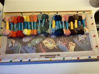 Overall view of canvas on frame with wool skeins pinned along top edge