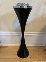 Full view of black pedestal ashtray stand against wall