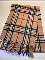 Full view of camel plaid scarf with fringe