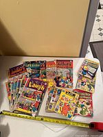Overall view showing mix of Archie and Richie Rich digests and standard comics with measuring tape for scale