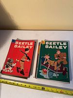 Stack of Beetle Bailey comics, red cover issue on top, measuring tape for scale