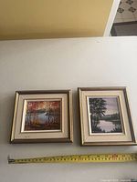 Front view of both framed paintings with tape for scale