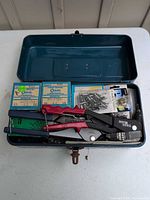 Open steel toolbox showing two rivet guns, boxed and loose rivets