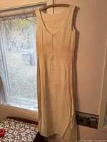 Full view of cream sleeveless nightgown hanging, showing length and front zipper