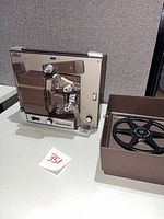 Front view of projector with open film path and accessories visible