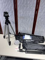 Overall view of Ambico tripod, MountDog bags, LED light, remote, paperwork on table