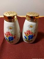 Front view of both shakers showing floral design and gold caps