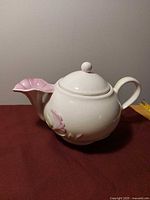 Full view of white ceramic teapot with floral spout and applied flower décor