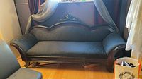 Full front view of the Victorian settee with carved crest and damask upholstery