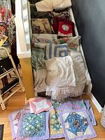 Staircase filled with assorted blankets, quilts, curtain panels and placemats
