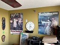 Wall with two Shaw Festival posters, wall clock, unframed prints on floor
