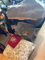 Stacked needlepoint panels and footstool showing sizes and patterns