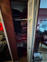 Full linen closet showing stacked towels and mats