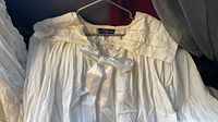 White cotton nightgown hanging, showing pleated front and tag