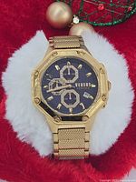 Front view of Versus Versace Kowloon gold-tone watch on display cushion showing dial, bezel and bracelet