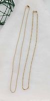 Both yellow gold chains coiled to show full lengths