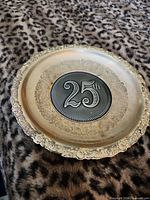 front view showing ornate rim and raised 25th medallion