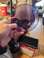 Hand holding amethyst glass bowl to show interior color and translucency