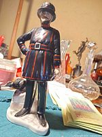 Front view of Coalport Beefeater figurine showing uniform, raven, and base.