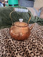 Front view of hammered copper kettle showing ceramic handle and knob