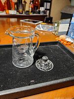 Pitcher with lid placed on table, showing etched pattern and lid separated