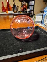 Side view of spherical rose glass vase on black surface