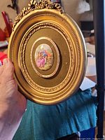 Front view of gold-tone oval frame with romantic couple print