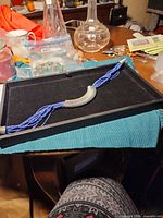 Necklace displayed on tray showing blue seed bead strands and silver-tone center tube