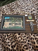 Front view of full plaque showing photograph, crest, bird and chain hanger