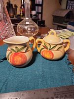 Creamer and sugar bowl on table with ruler for scale