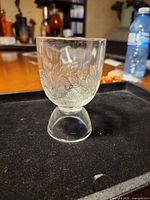 Front view of clear pressed glass egg cup with blackberry pattern