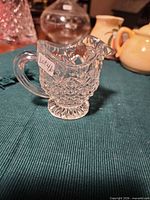 Side view of pressed glass creamer showing handle, spout, diamond pattern