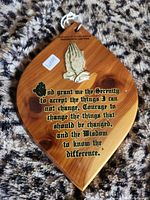 Front view showing plaque shape, text, metal praying hands, hanging cord