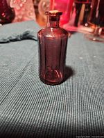 Front view of small amethyst glass bottle standing upright