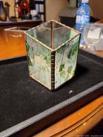 Front perspective of stained glass cube showing green glass and brass came