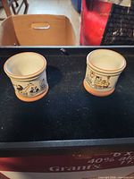 Front view of two porcelain egg cups showing zoo train illustrations