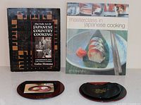 Front covers of both cookbooks with two lacquer plates displayed