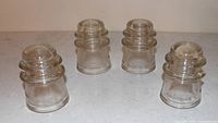 Four Dominion clear glass insulators front view