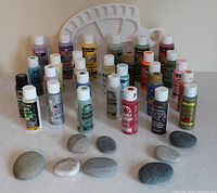 All items in lot: acrylic paint bottles, palette, rocks