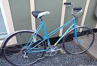 Full left side view of blue Apollo step-through bicycle showing frame, wheels, drivetrain, handlebars and fenders