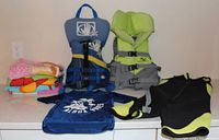 Entire lot on countertop showing life jackets, towel stack, wetsuit, rashguard