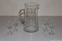 Front view of clear etched glass pitcher with four sherry glasses